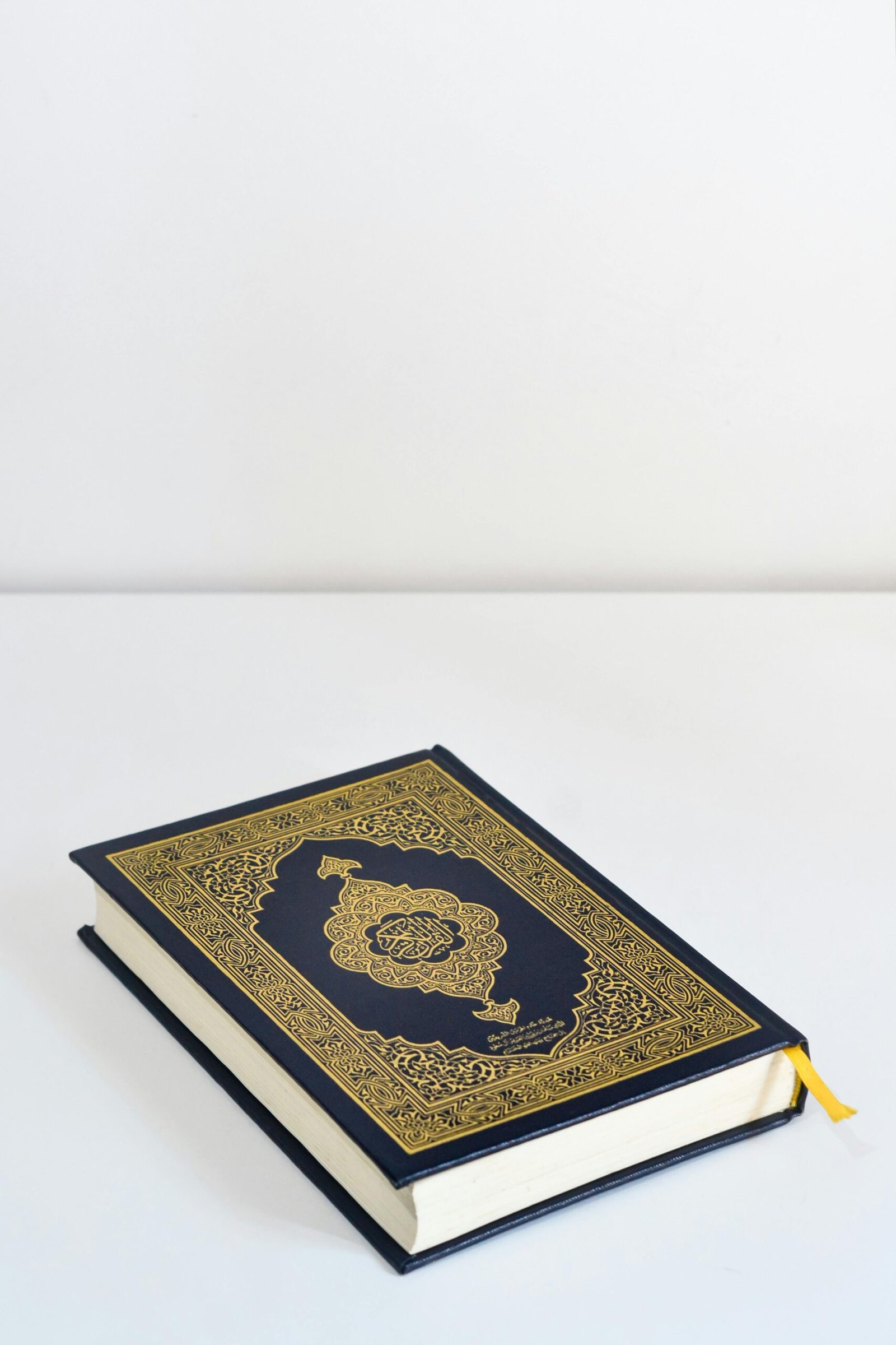 Close-up of a beautifully designed Quran with a gold embossed navy blue cover on a simple desk.